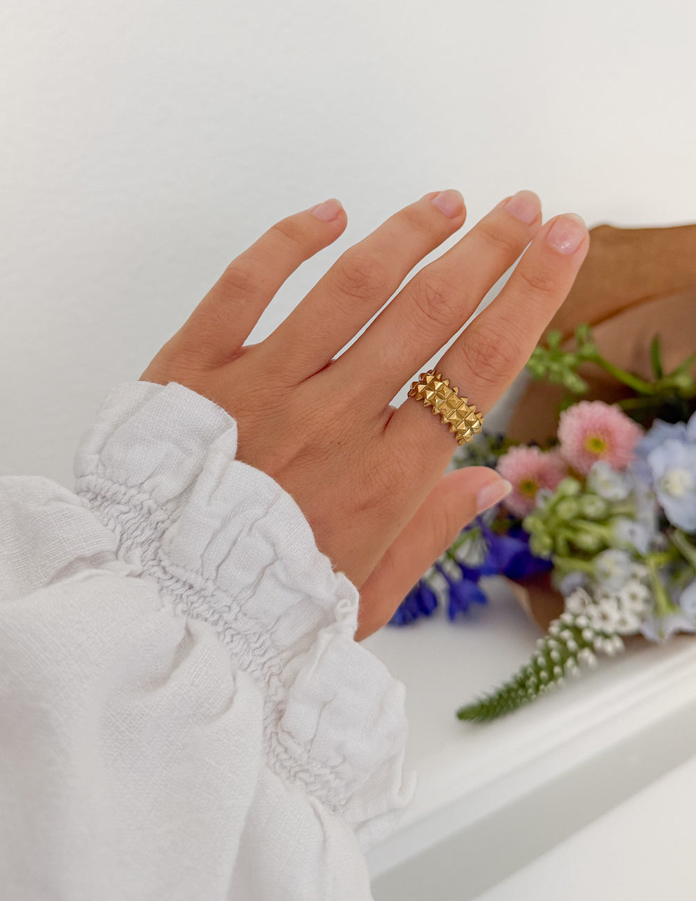 Gold-tone textured shield ring on finger