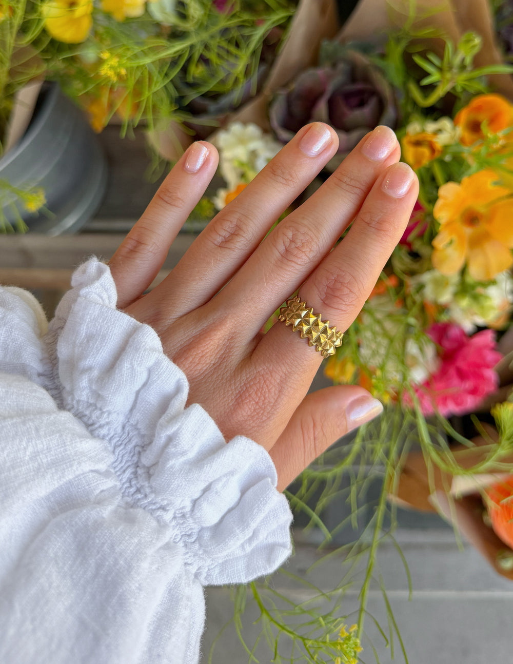 Gold-tone raised shield-pattern ring on finger
