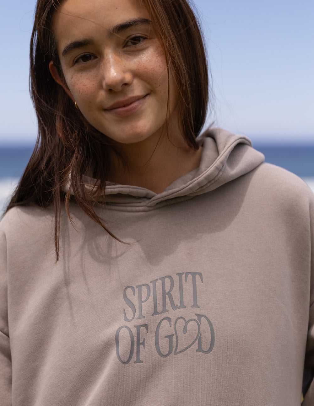 Taupe unisex hoodie close-up with 'Spirit of God' chest print and drawstring hood