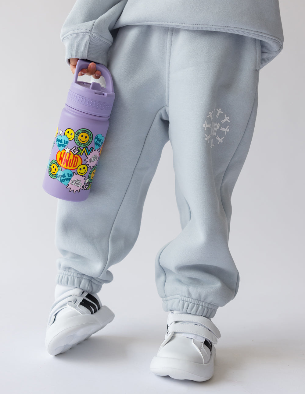 Lavender kids water bottle with sticker collage, clipped in hand while standing