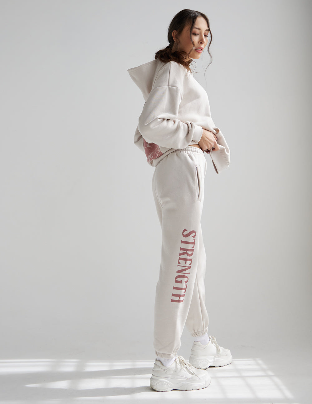 Cream unisex sweatpants with red STRENGTH leg print, elastic waist and relaxed straight legs