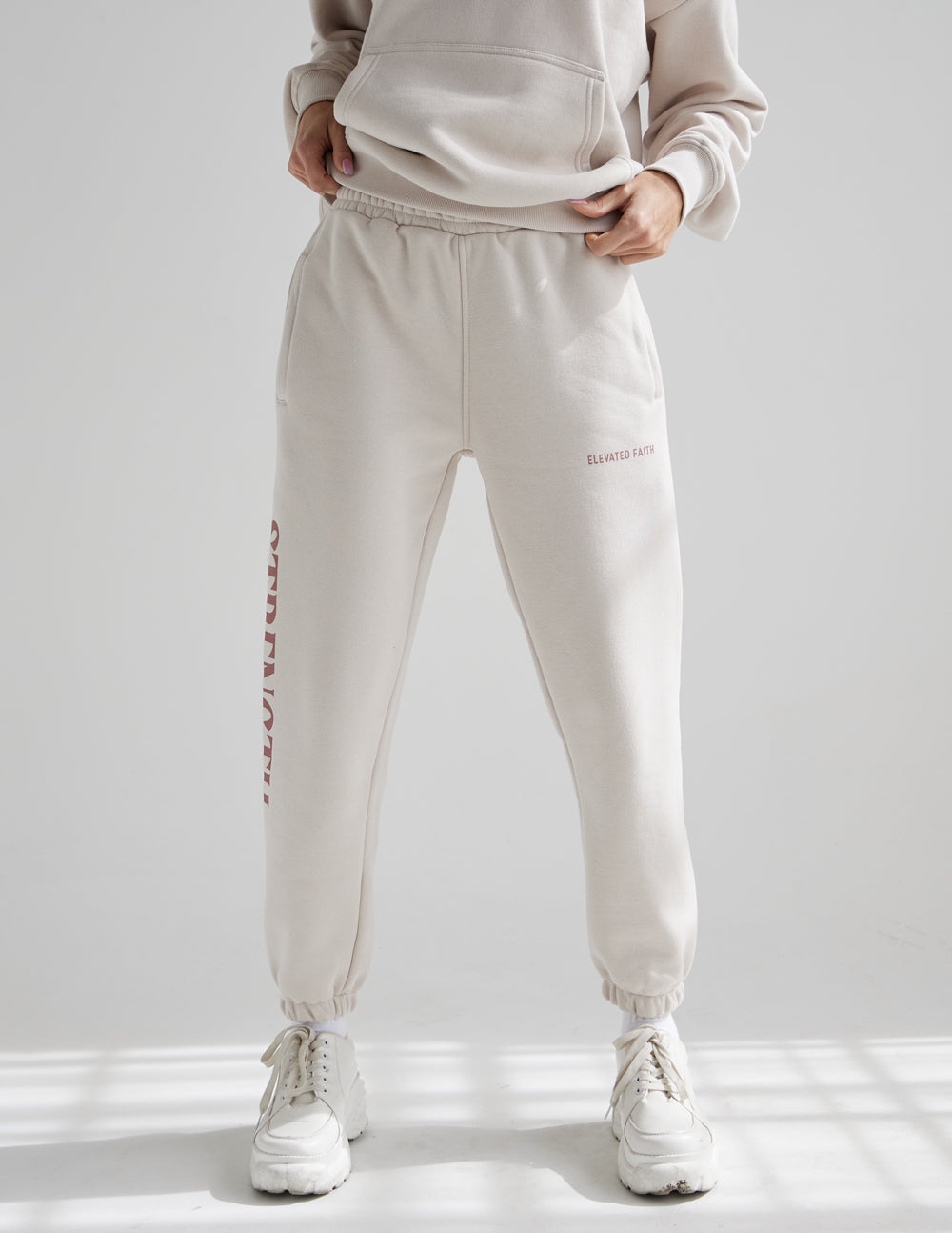 Cream unisex sweatpants with small chest logo and vertical red STRENGTH side print