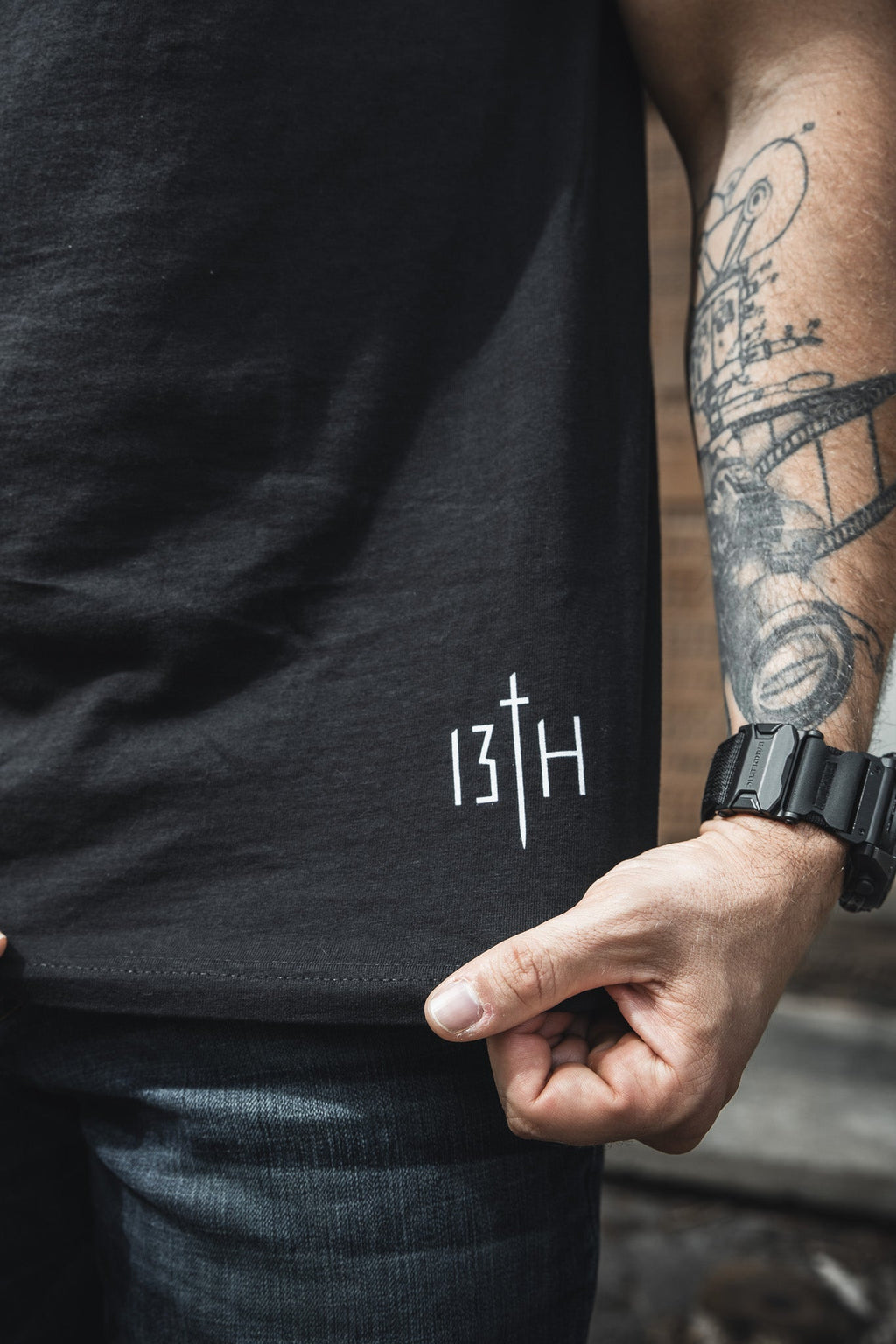 Black t-shirt sleeve and chest area with small “13th” print