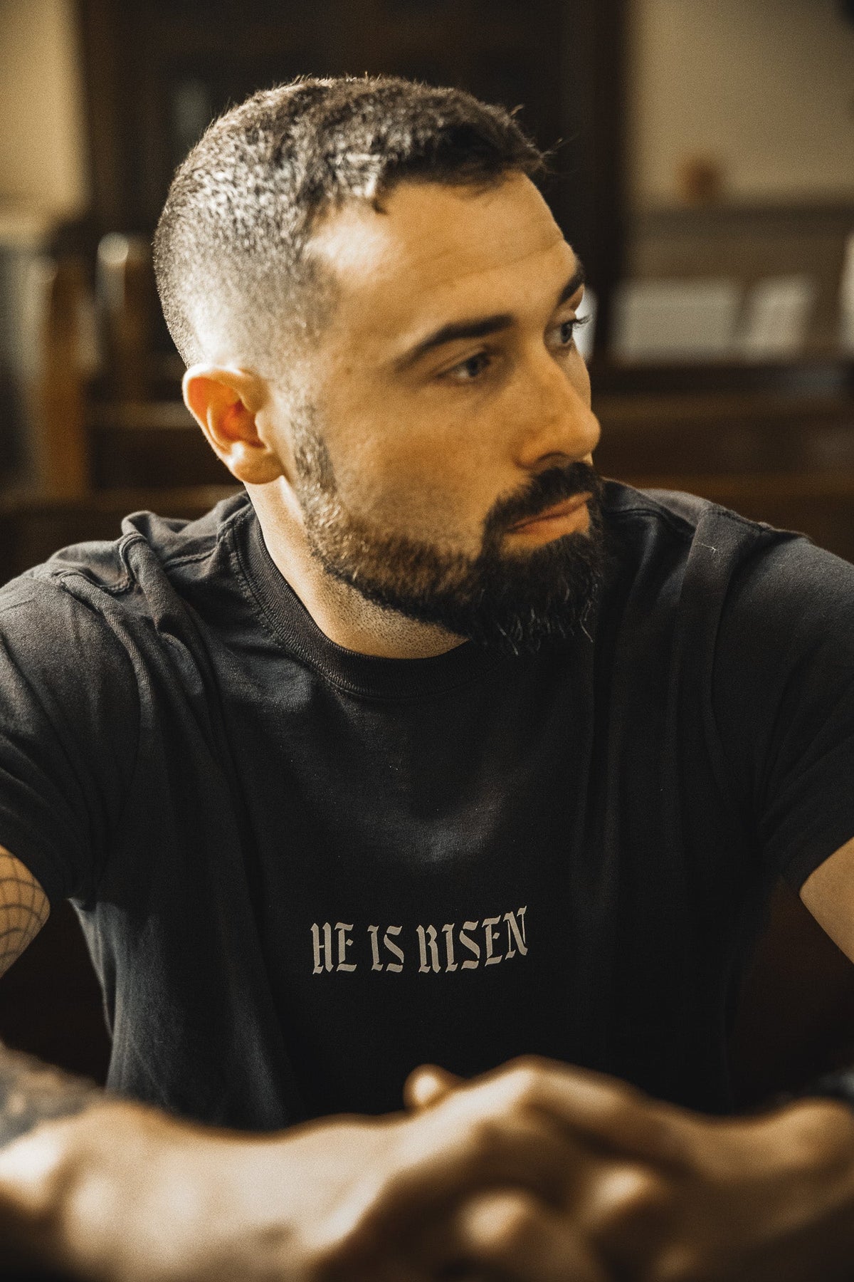 Black crew-neck t-shirt with “HE IS RISEN” front text