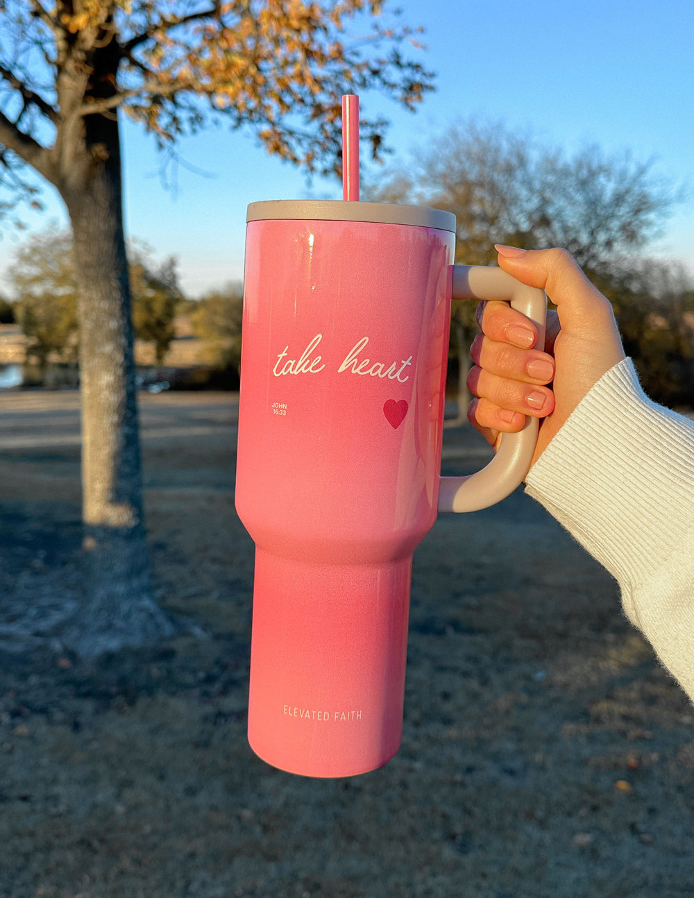 40 oz Ascend tumbler, pink with beige lid and red straw, held by a hand