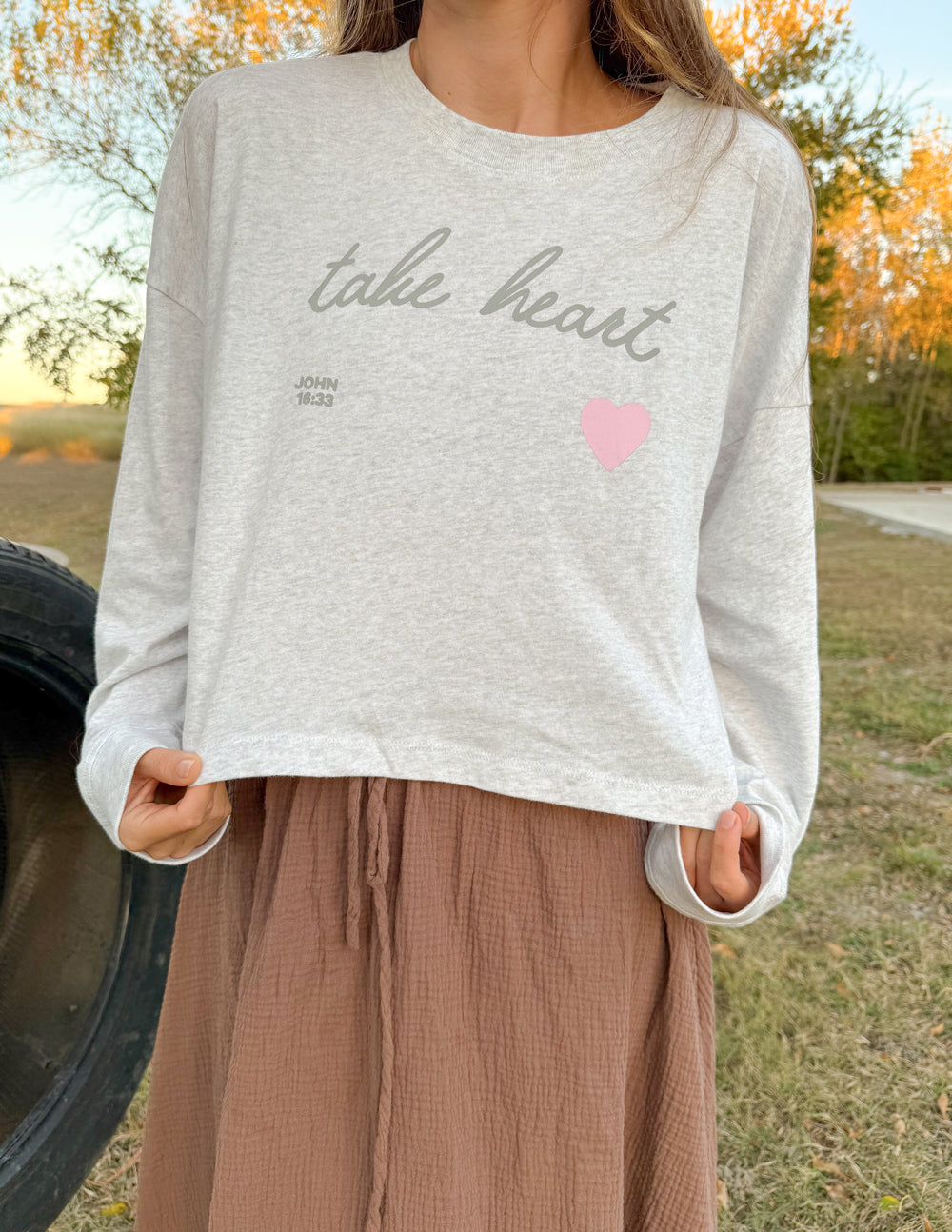 Light gray cropped long-sleeve tee with script logo and pink heart print on front