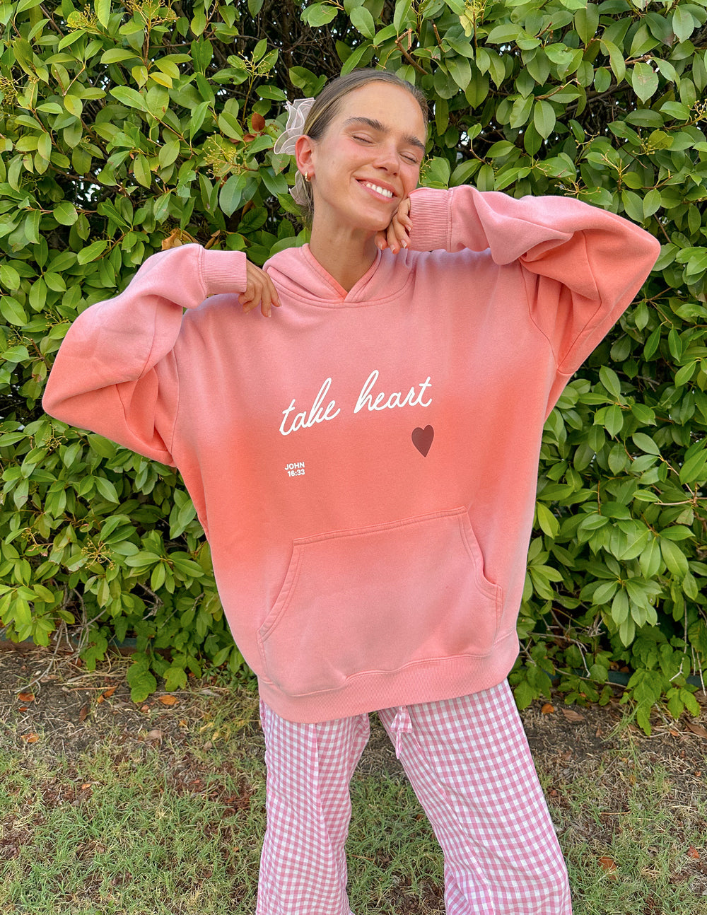 Pink unisex hoodie with 'take heart' script and heart graphic, front kangaroo pocket