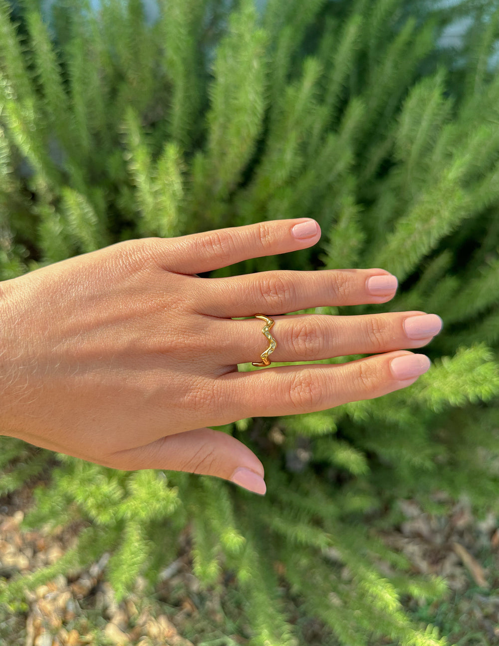 Gold-tone textured wavy band ring on finger, wavy profile