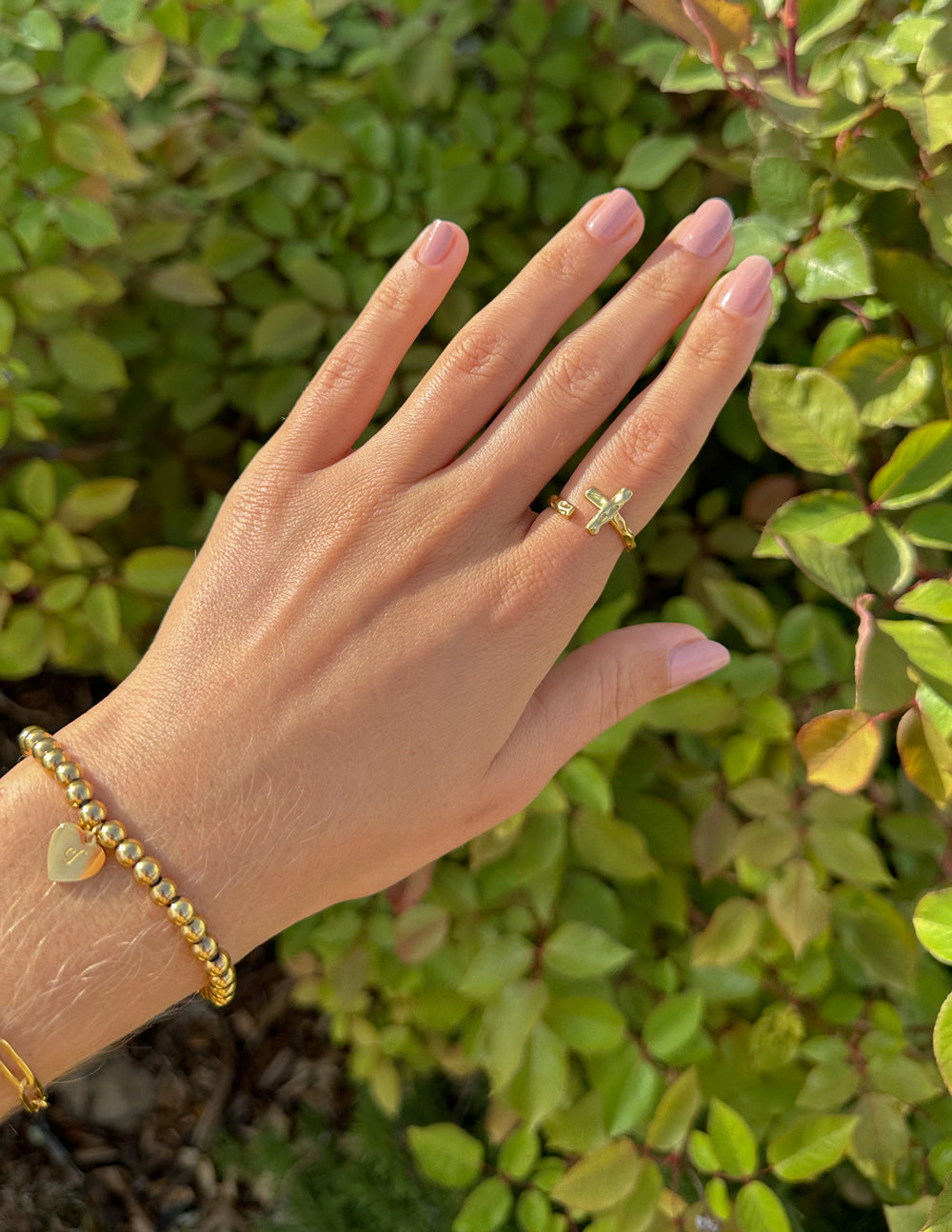 Gold textured cross ring on a finger, wrapped band detail visible