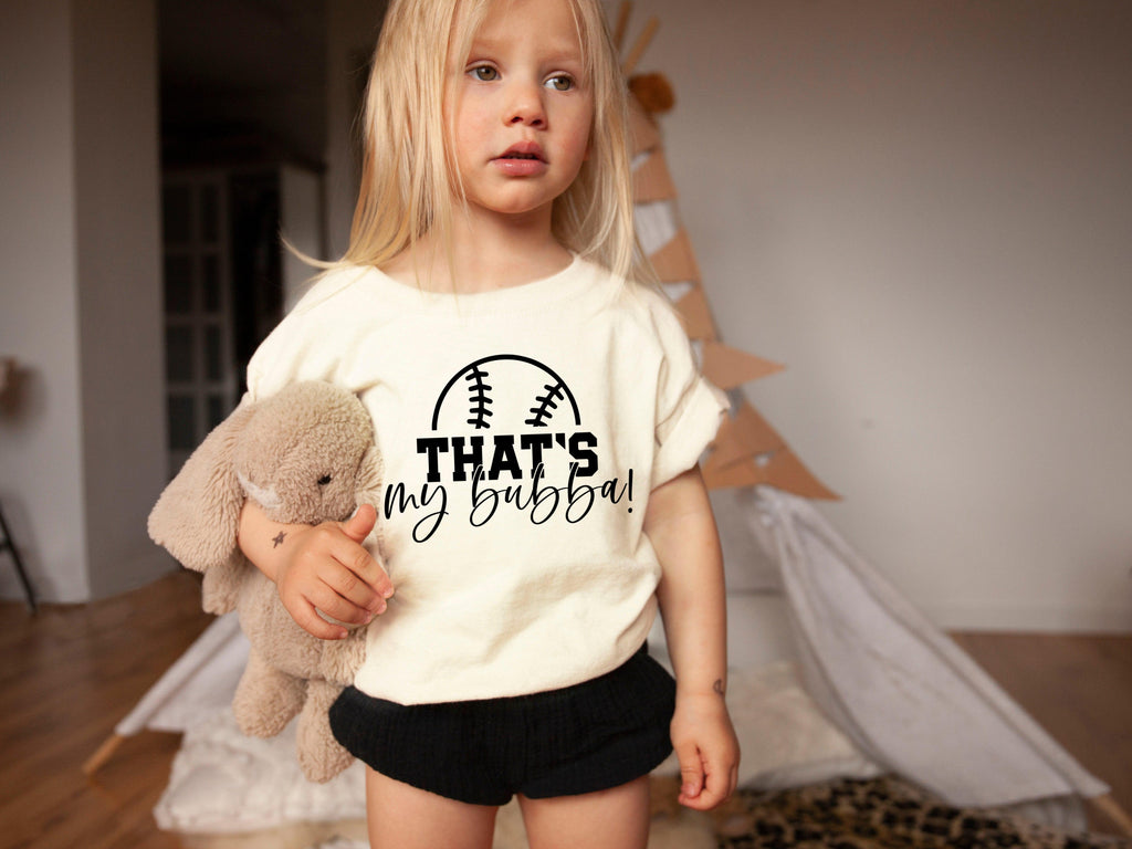 Cream kids graphic T-shirt with football logo and text "THAT'S my bubba!"
