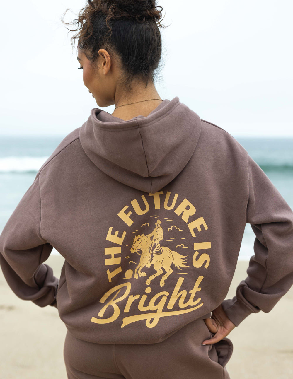 Mauve unisex hoodie with hood and gold rodeo graphic on back, kangaroo pocket.