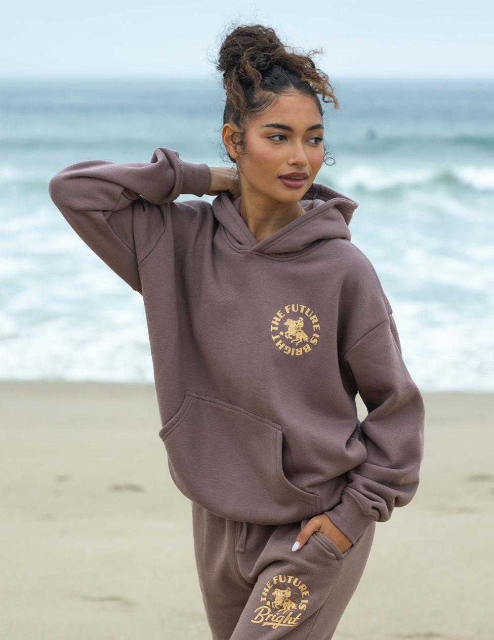 Mauve unisex hoodie with hood, kangaroo pocket, and gold rodeo graphic on chest.
