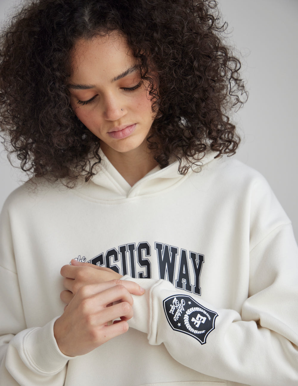 Unisex white hoodie close-up with “JESUS WAY” chest print and sleeve crest patch