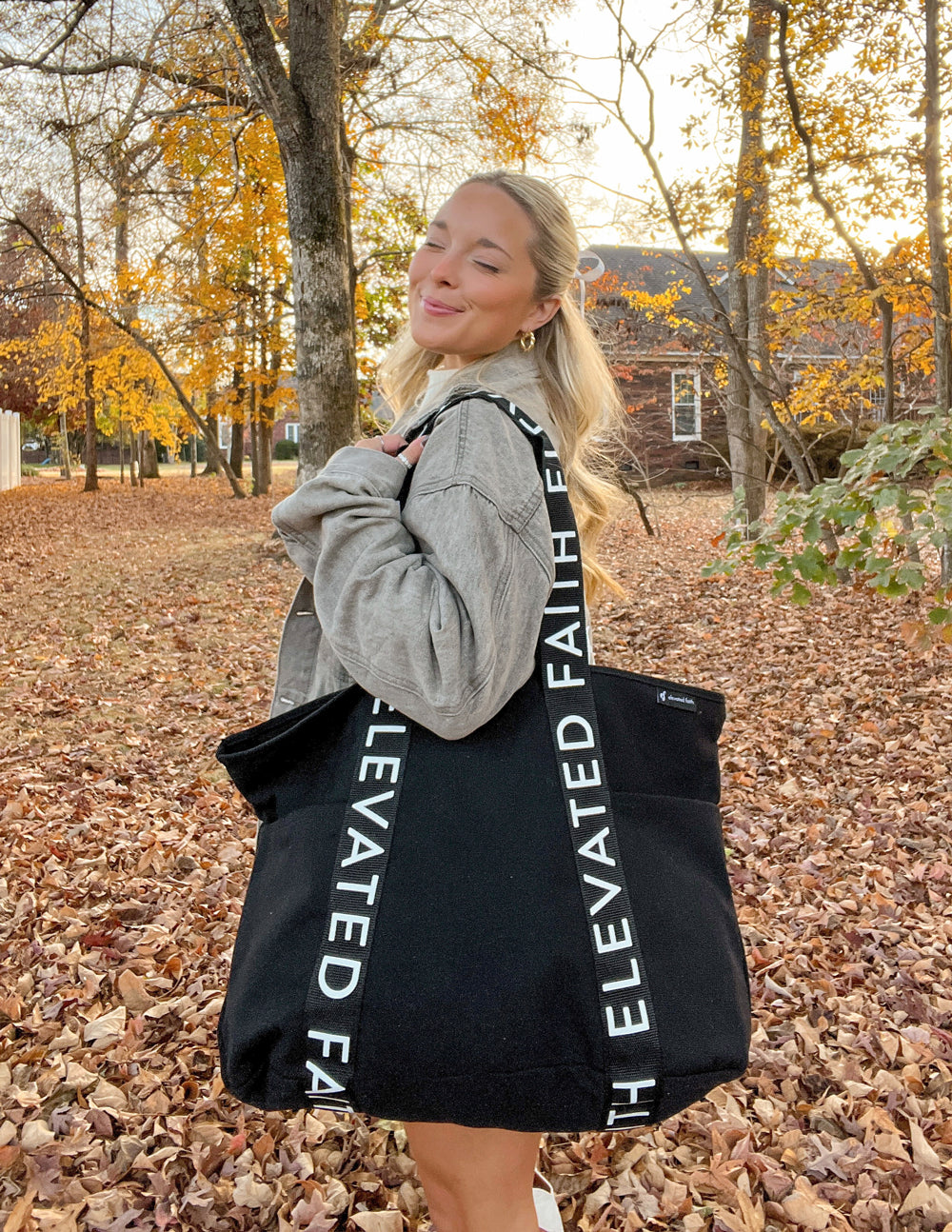 Black large tote bag with bold “ELEVATED FAITH” lettering on both handles