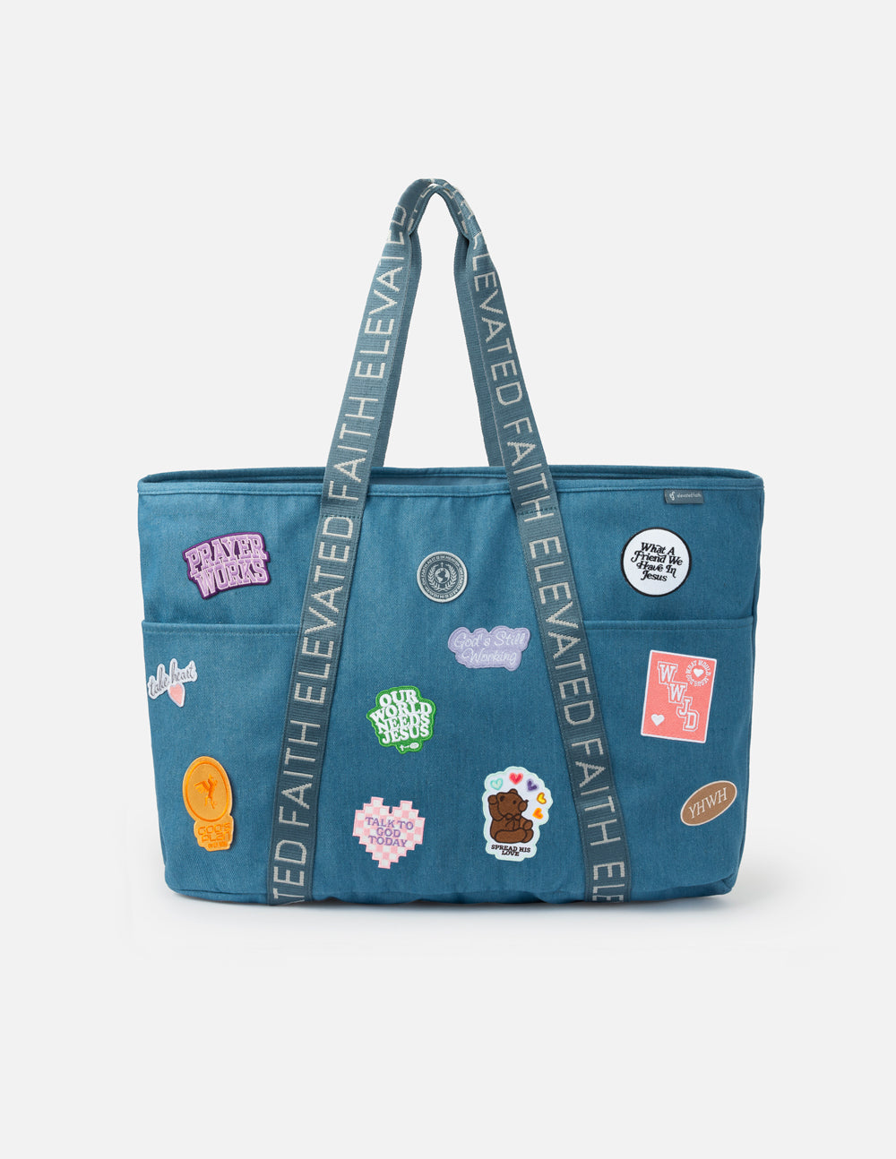 Blue denim tote bag with colorful faith-themed patches and front circular logo badge