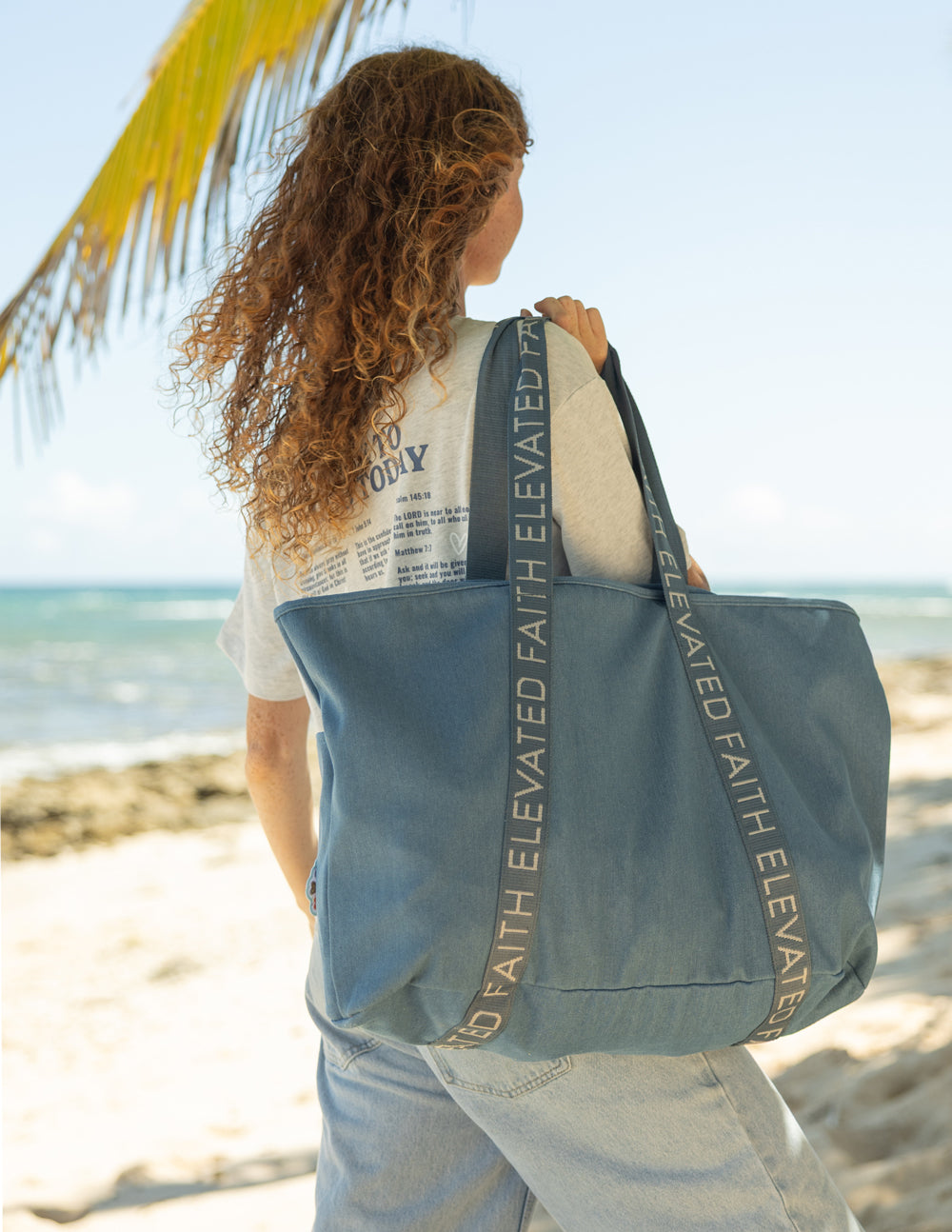 Blue denim tote bag back view with ELEVATED FAITH webbing strap