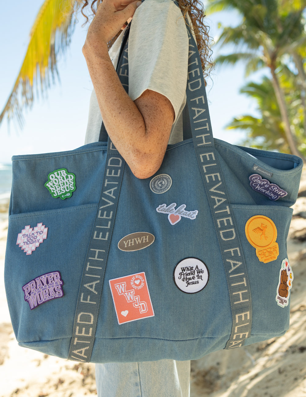 Blue denim tote bag front close-up with embroidered patches and circular emblem