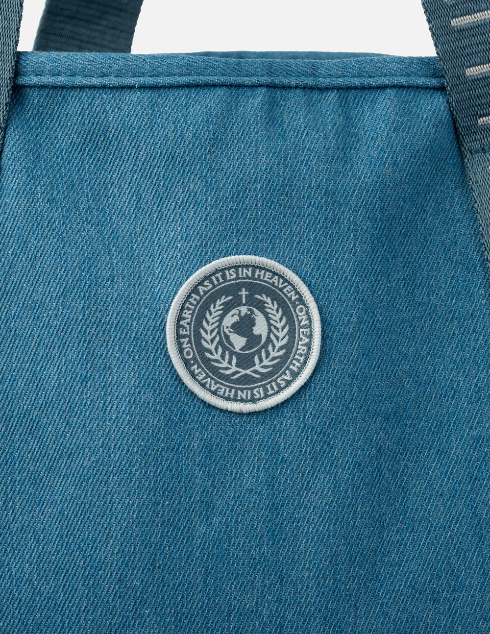 Circular logo patch on the front of a blue denim tote bag