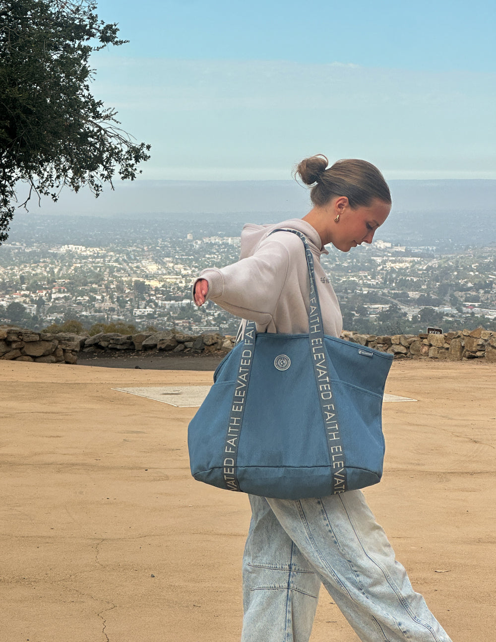 Blue denim tote bag with long handles and printed logo text on straps