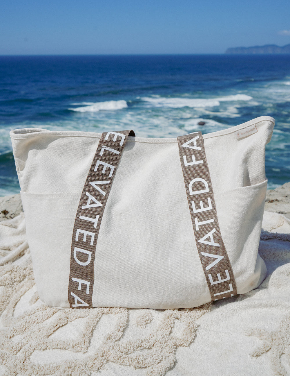 Large everyday tote on sand with cream canvas and brown vertical logo straps