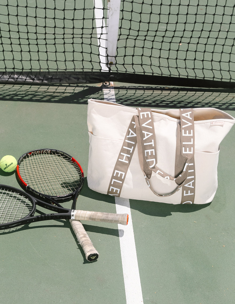 Large everyday tote on tennis court bench, cream canvas with brown logo webbing