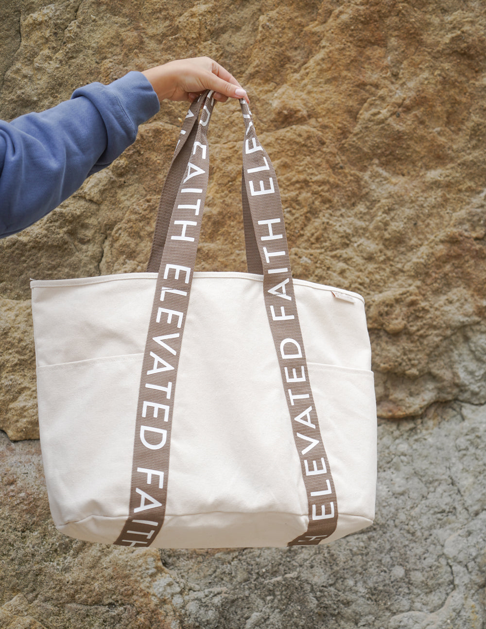 Large everyday tote on rocks held by brown logo webbing handles, cream canvas
