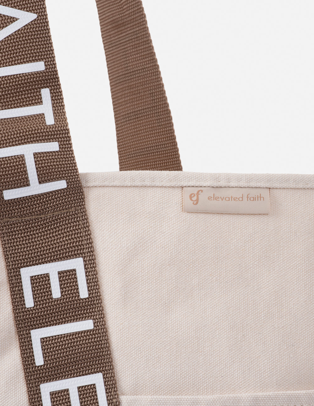 Cream tote bag with brown woven side strap and 'elevated faith' fabric label