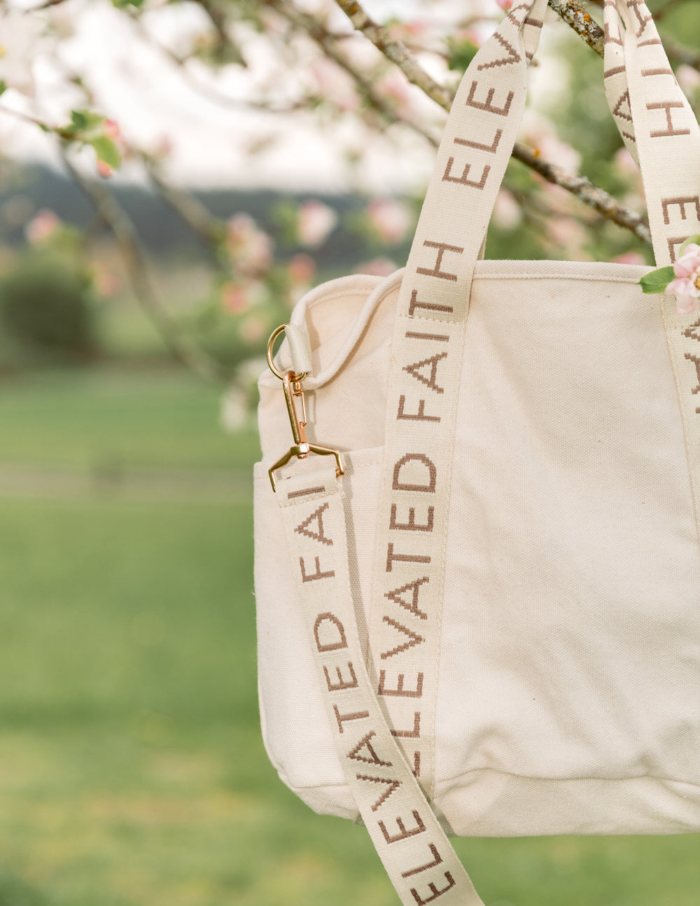 Cream mini tote with front panel and “ELEVATED FAITH” strap lettering detail