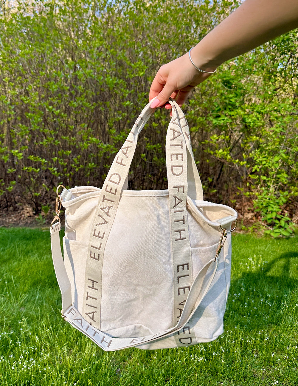 Cream mini tote with two top straps and “ELEVATED FAITH” print on handles