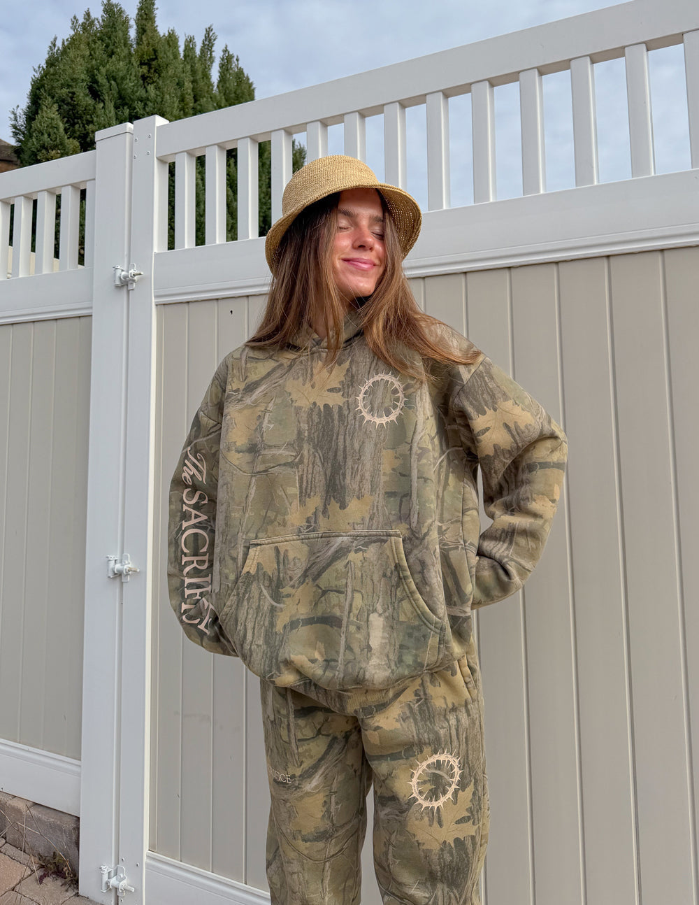 Camouflage unisex pullover hoodie with “Sacrifice” sleeve print and circular chest graphic