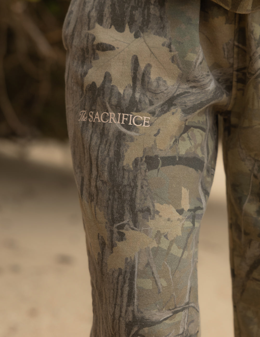 Camo sweatpants with 'THE SACRIFICE' logo text on thigh