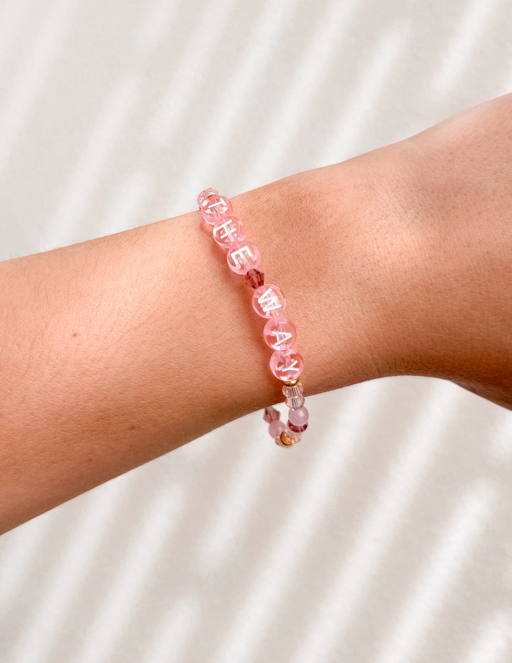 Pink beaded letter bracelet with faceted cubes spelling letters