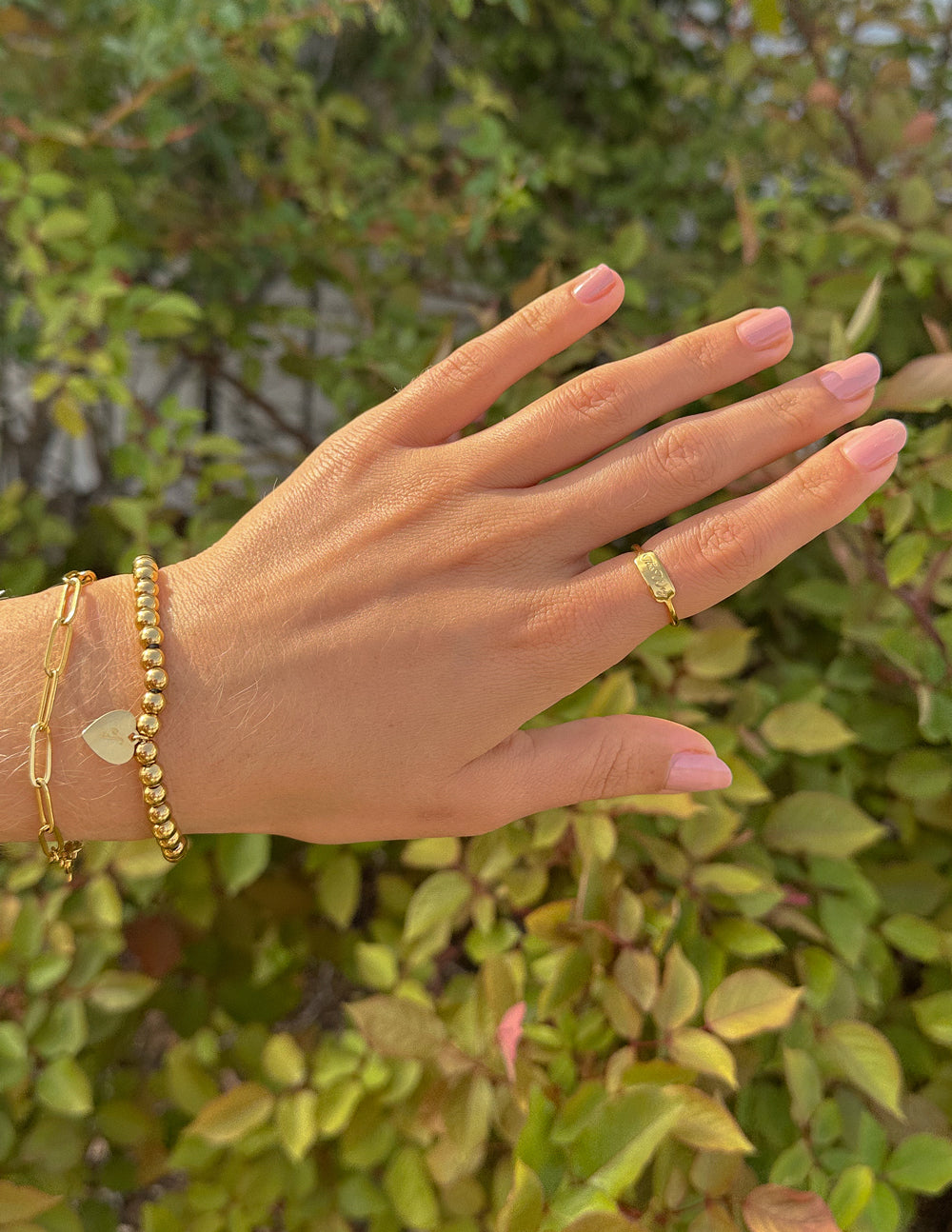Gold tone signet ring and slim band on hand