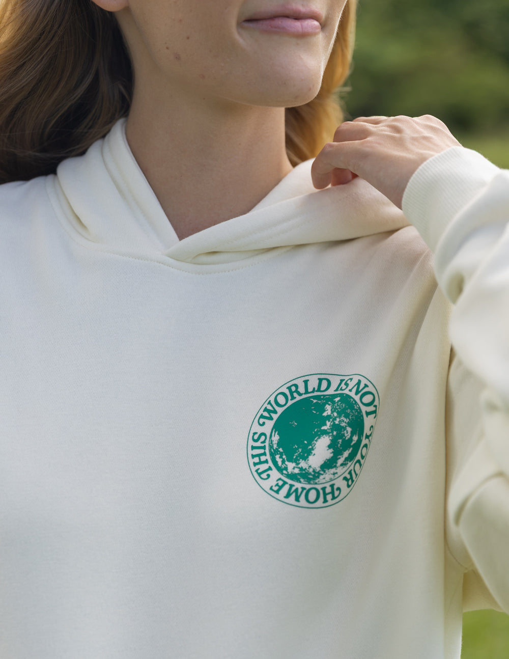 Light cream unisex hoodie close-up with green chest logo