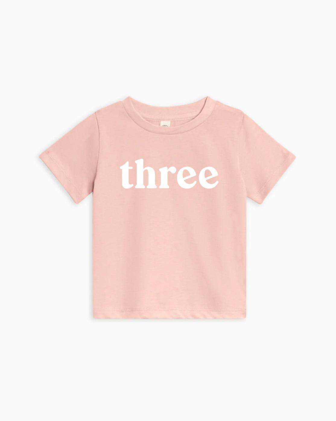 Kids organic cotton T-shirt in pink with white 'three' text on front