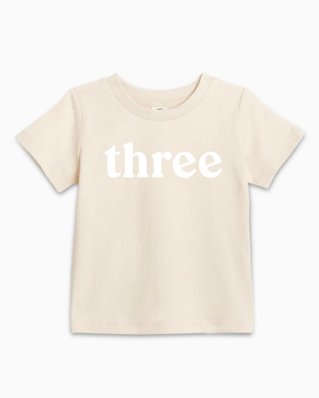 Kids organic cotton T-shirt in light cream with white 'three' text on front
