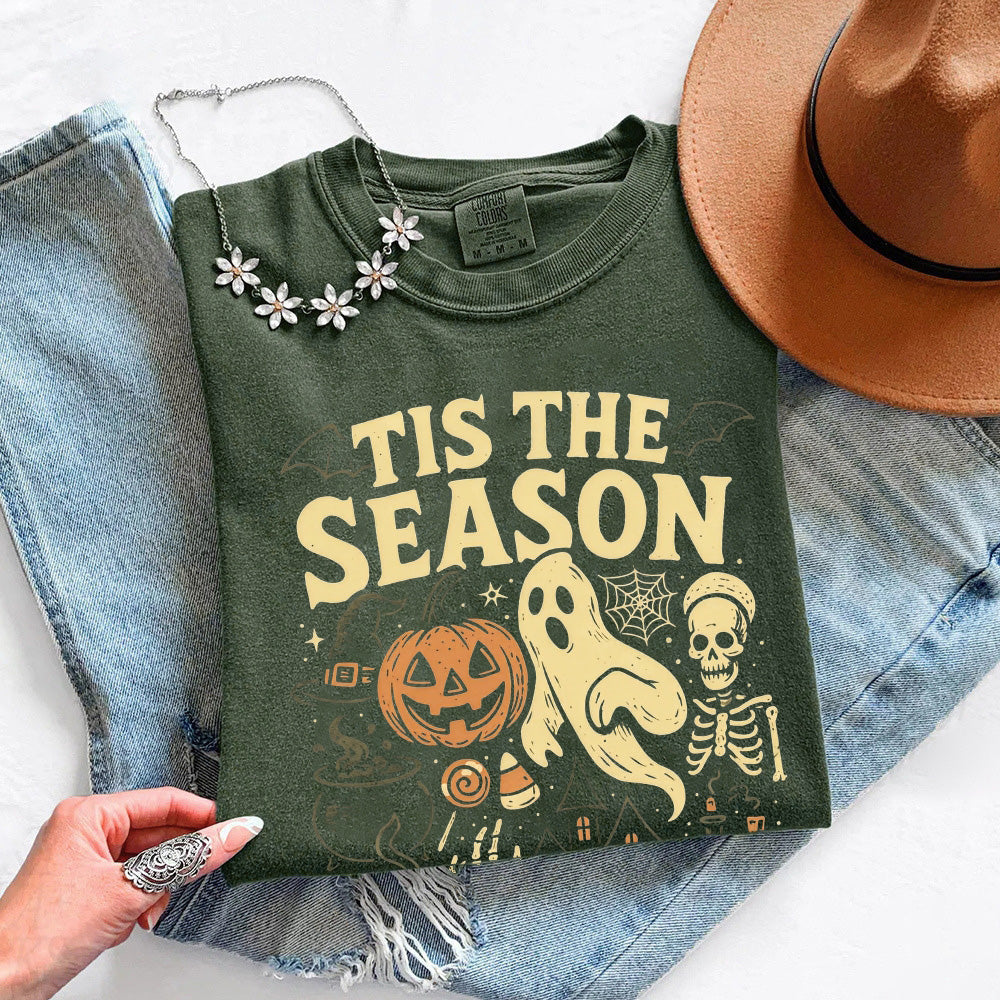 Dark green crewneck T-shirt with “Tis the Season” Halloween graphic, folded view