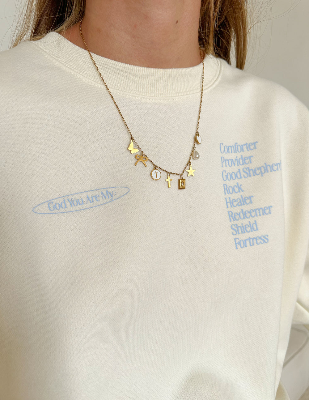Gold-tone charm necklace with stars, cross, and heart pendant on chain