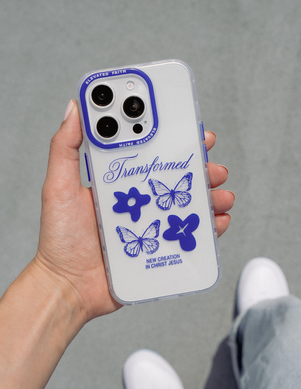 Clear phone case with blue butterflies and cross graphic, shown in hand