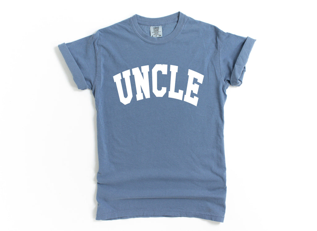 Blue T-shirt with large white “UNCLE” graphic on the chest.