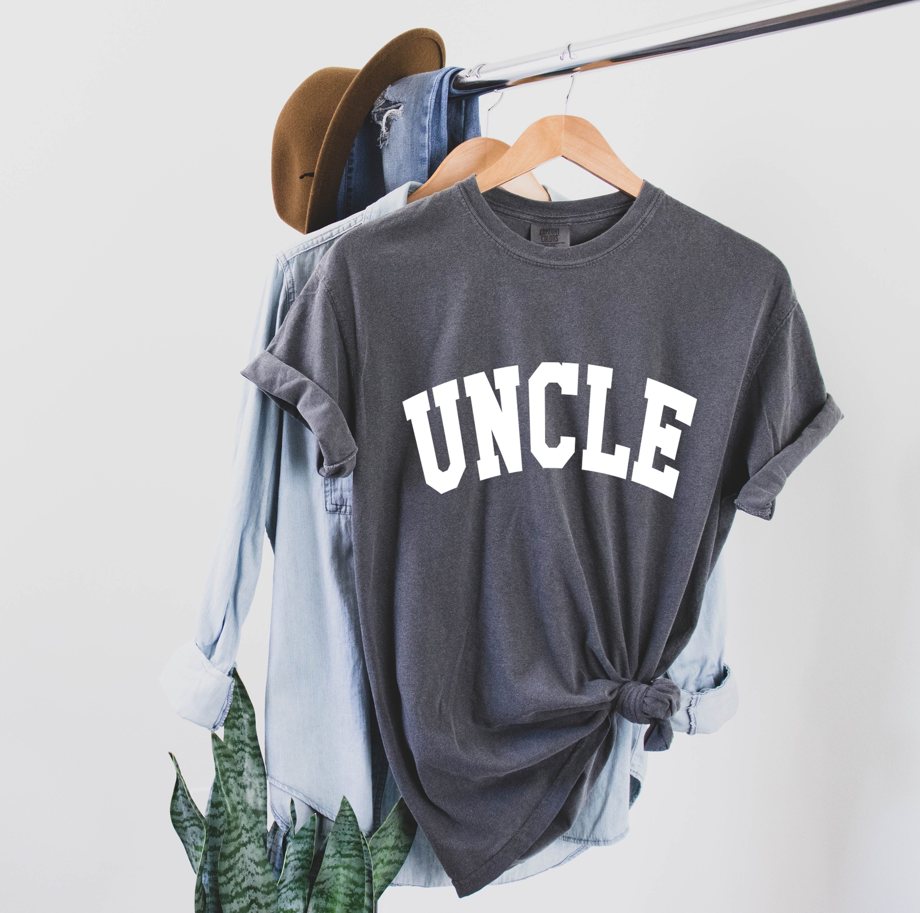 Dark gray T-shirt with large white “UNCLE” graphic on the chest.
