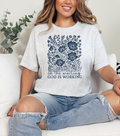 Light gray women's graphic T-shirt with blue floral tree and 'God is working' print