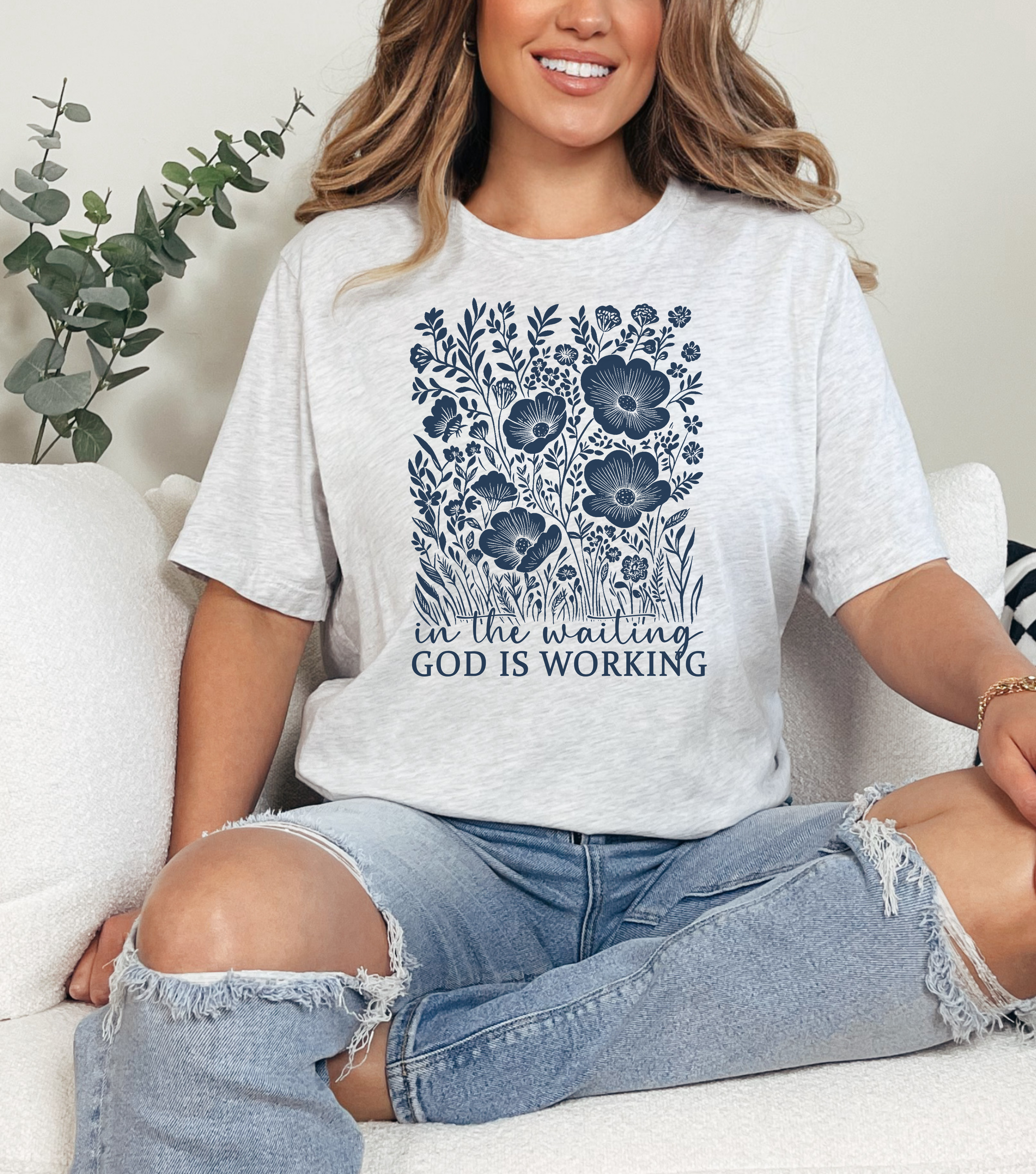 Light gray women's graphic T-shirt with blue floral tree and 'God is working' print