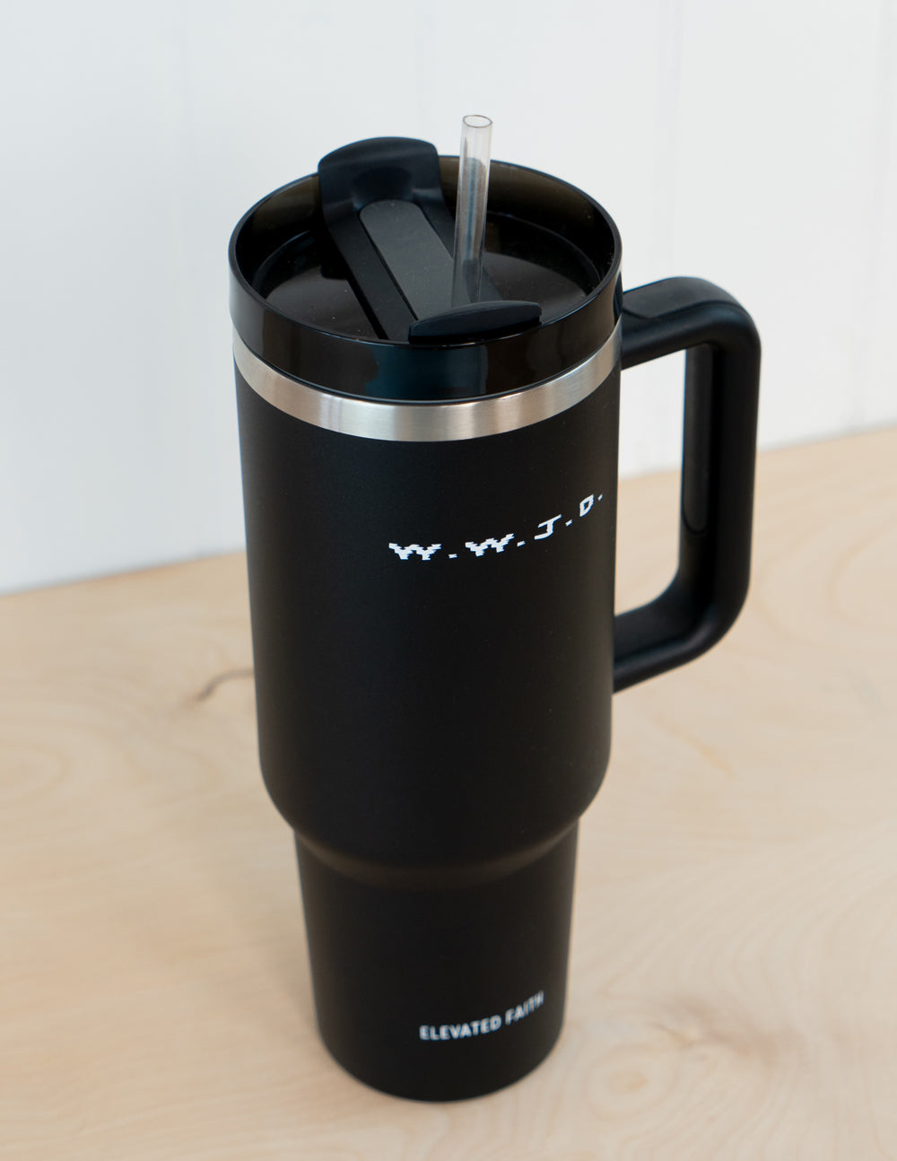 Black insulated tumbler with open lid, straw, and drink-access top, WWJD logo on front.