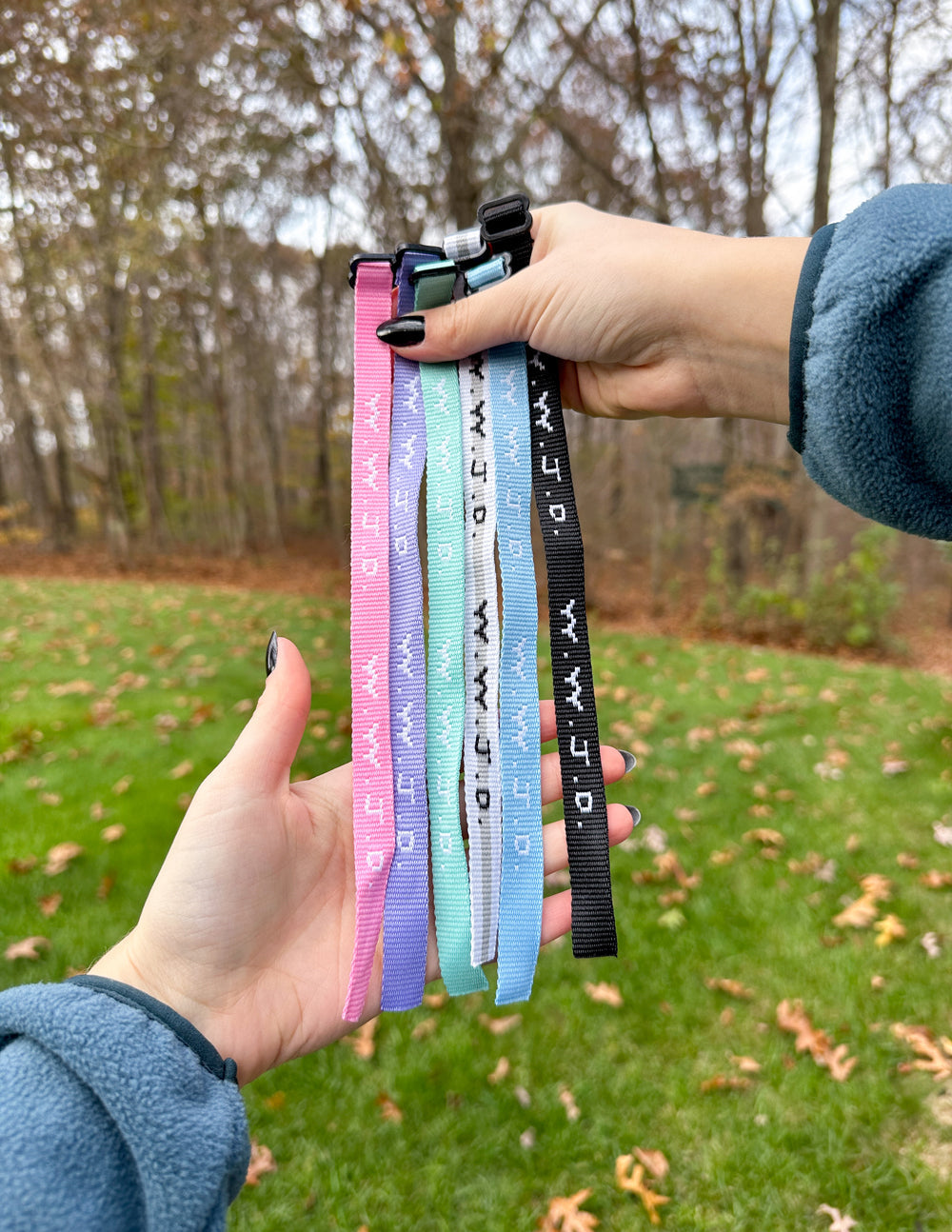 Hand holding a bundle of woven WWJD-style friendship bracelets in mixed colors