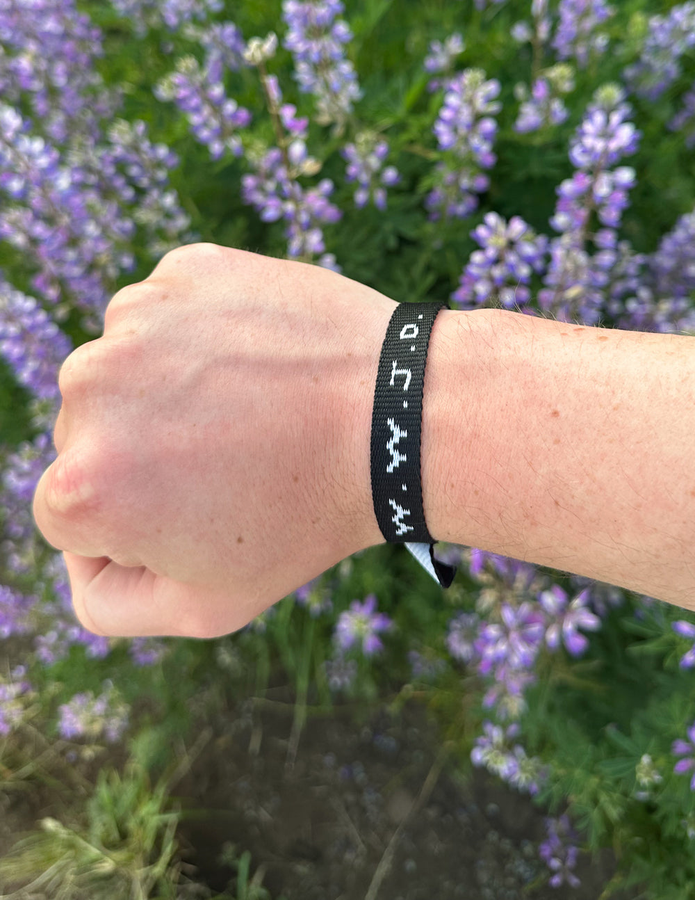 Black fabric bracelet with white text symbols and adjustable woven ends