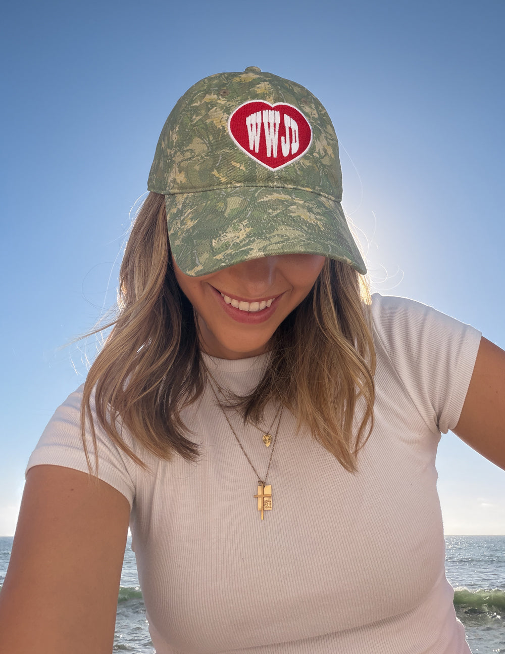 WWJD camo baseball cap with red heart logo patch, close-up front