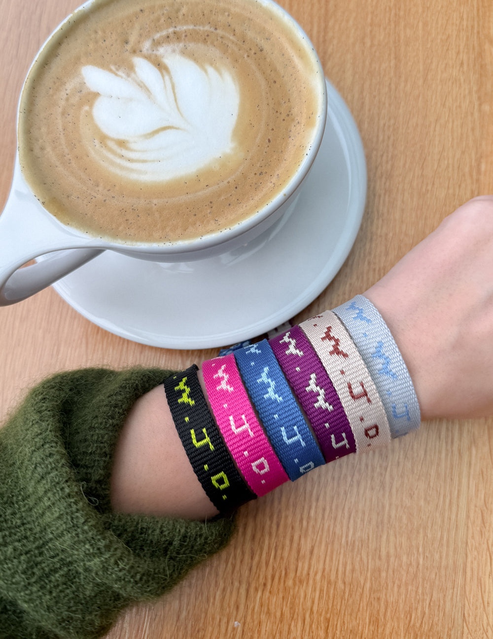 Wrist wearing woven cyber charm bracelet with blue, black, pink, and white stripes.