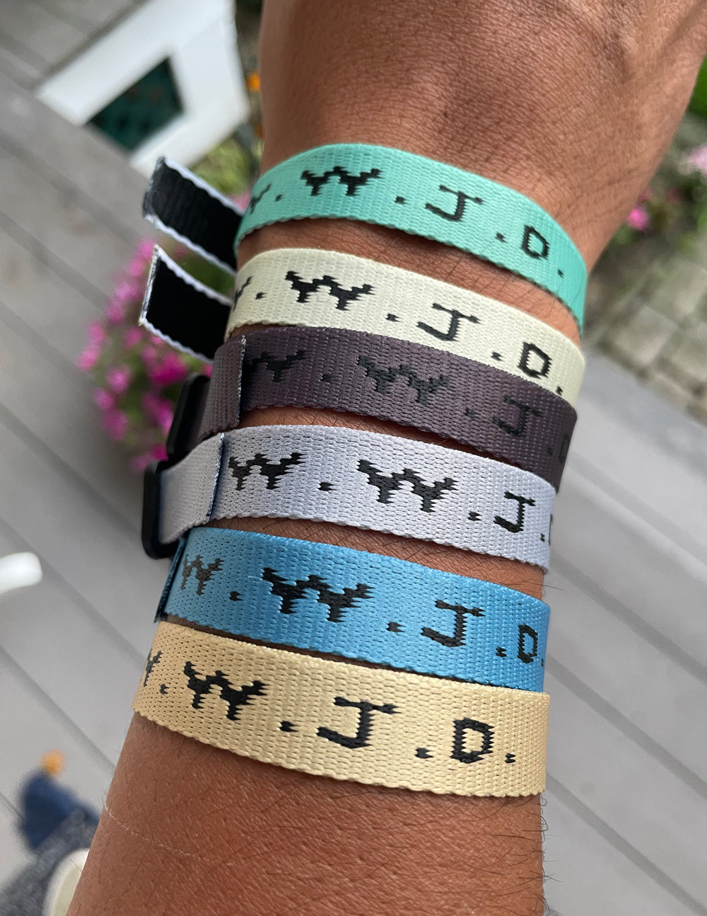Close-up of stacked fabric surf bracelets with WWJD print on wrist