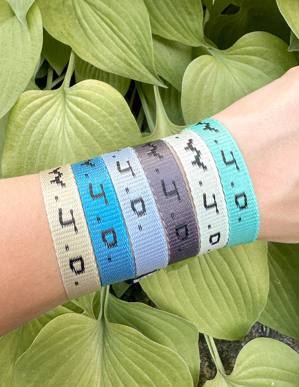 Close-up of fabric surf bracelet with WWJD print on wrist, turquoise and cream